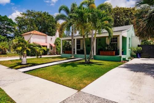 een huis met palmbomen in de tuin bij Key Lime Cottage - Bask Poolside in a Historic Flamingo Park Gem in West Palm Beach