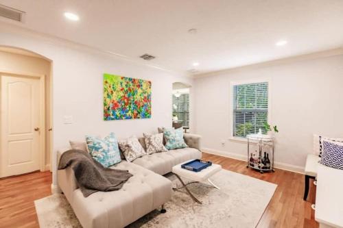 een woonkamer met een bank en een schilderij aan de muur bij Key Lime Cottage - Bask Poolside in a Historic Flamingo Park Gem in West Palm Beach