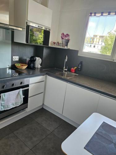 une cuisine avec des armoires blanches et un évier dans l'établissement F2 avec grand balcon quartier gare!, à Metz