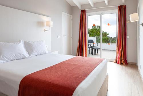 a hotel room with a bed and a balcony at Minura Sur Menorca in Punta Prima