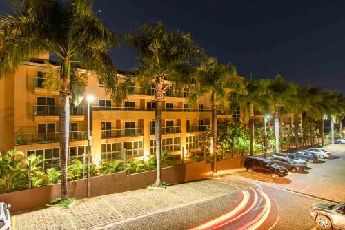 un edificio con palmeras y coches aparcados en un aparcamiento en Life Resort Hotel em Brasília 49259, en Brasilia