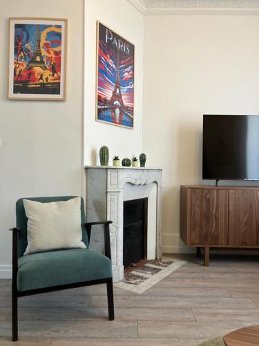 un salon avec une télévision et une chaise dans l'établissement Charmant appartement décoré proche du parc des expositions, à Paris