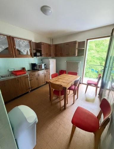 une cuisine avec une table en bois et des chaises rouges dans l'établissement Borée, à Thollon-les-Mémises