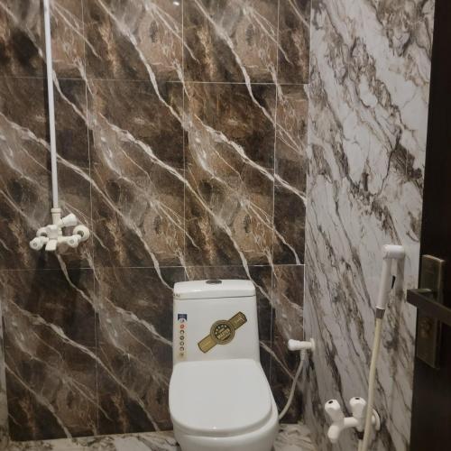 a bathroom with a toilet with a brown stone wall at White Palace Hotel in Karachi