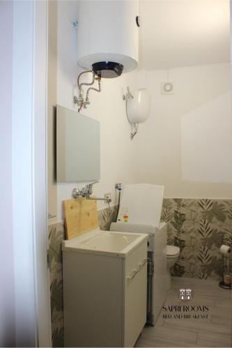 a bathroom with a sink and a light on the wall at Sapri Rooms in Lamezia Terme