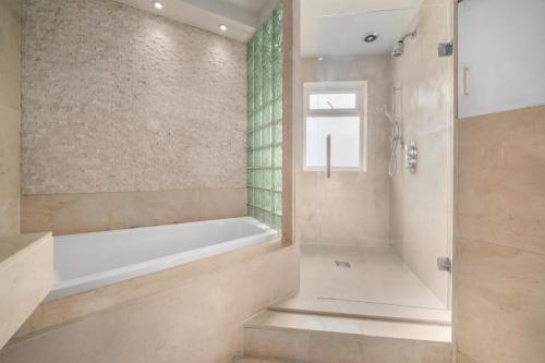 ein Badezimmer mit Badewanne und Dusche in der Unterkunft Spacious 4BR House with Parking, Garden & 500Gb WiFi in London