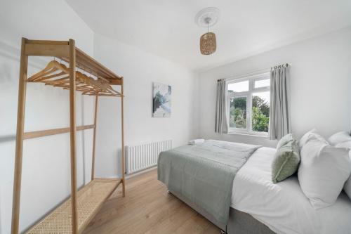 ein weißes Schlafzimmer mit einem Bett und einem Fenster in der Unterkunft Spacious 4BR House with Parking, Garden & 500Gb WiFi in London