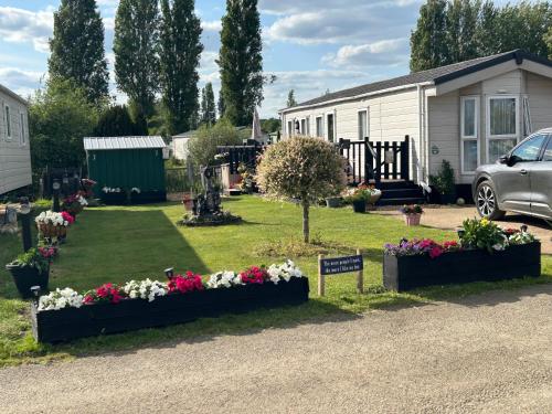 a garden with flowers in front of a house at Billing Aquadrome Holiday Park in Great Billing