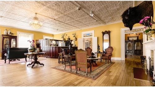a large living room with chairs and a piano at William F Cody - Historic Hotel in Cimarron