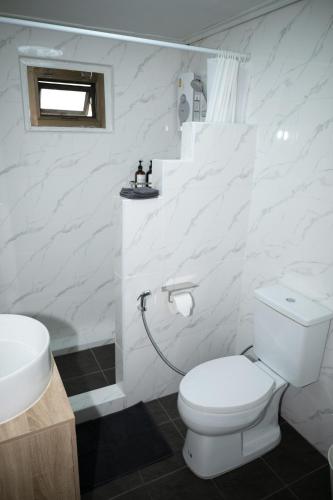 a white bathroom with a toilet and a sink at Urban Grace in Bangkok