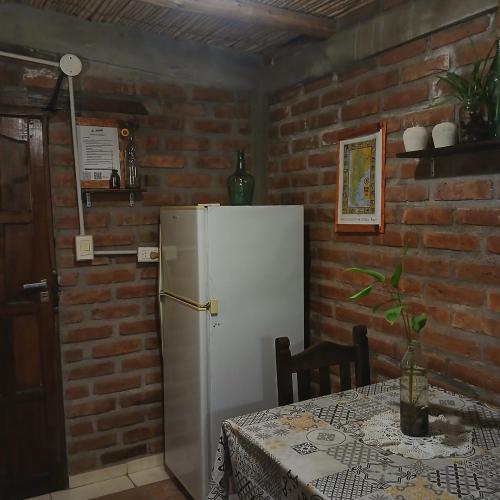 a kitchen with a table and a white refrigerator at Posada & Hostel La Soñada in Chilecito
