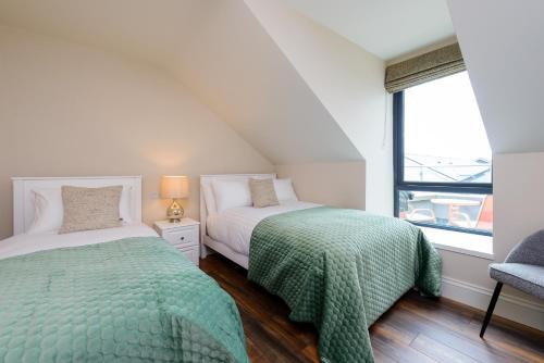 a bedroom with two beds and a window at Dingle Heritage Townhouse in Dingle