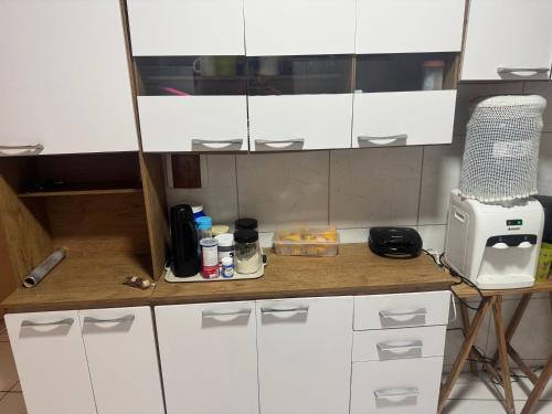 a kitchen counter with white cabinets and a microwave at Suite climatizada em Ap compartilhado na ponta da areia in Vinhais