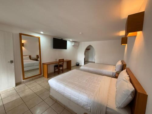 a hotel room with two beds and a mirror at Aldea del Bazar in Tehuacán