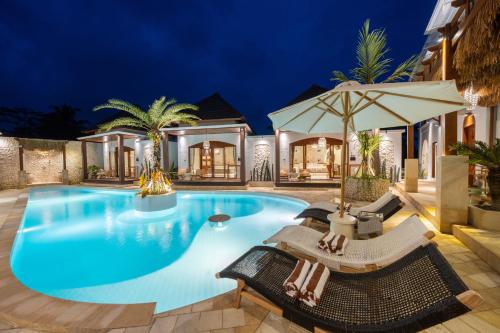 a swimming pool with chairs and an umbrella at Casa Maddu in Tegalalang