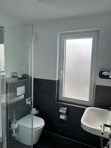 a bathroom with a toilet and a sink and a window at Hotel Restaurant Harrier Hof in Brake