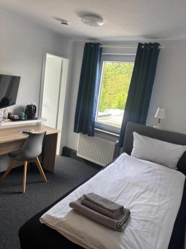 a bedroom with a bed with a desk and a window at Hotel Restaurant Harrier Hof in Brake