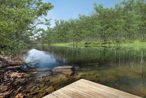a body of water with trees and a wooden dock at Waterfront w Hot Tub Fire Pit Deck & Water Toys in Great Cacapon