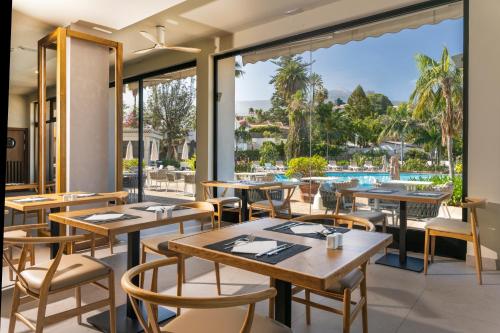 a restaurant with tables and chairs and a view of a pool at Hotel Atlantic El Tope in Puerto de la Cruz