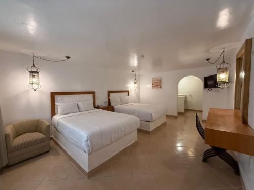 a bedroom with two beds and a chair and a desk at Aldea del Bazar in Tehuacán