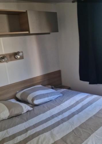 un lit avec deux oreillers dessus dans une chambre dans l'établissement Mobilhome chaleureux 8 couchages, à Pont-Aven