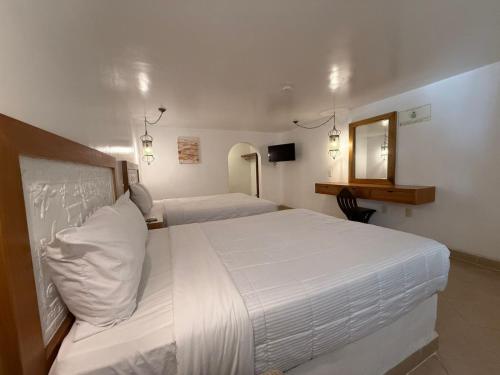 a hotel room with two beds and a mirror at Aldea del Bazar in Tehuacán
