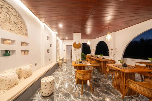 a restaurant with wooden tables and chairs and windows at Casa Maddu in Tegalalang