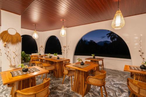 a restaurant with wooden tables and chairs and lights at Casa Maddu in Tegalalang