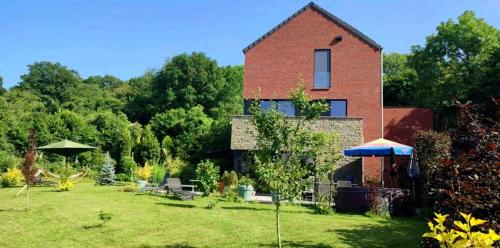 a brick house with a yard with tables and umbrellas at Fredhousedurbuy 1 in Durbuy