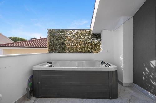 a bathroom with a bath tub on a balcony at Apartments 1 with pool and private jacuzzi in Vodice