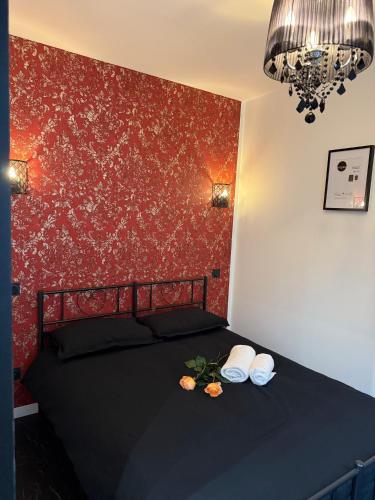- une chambre avec un lit noir et un mur rouge dans l'établissement Le secret du Moulin, à Paris