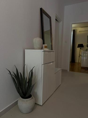 a white dresser with a mirror and a plant in a room at Villa Vida, Medulin - Bazen i jacuzzi in Medulin
