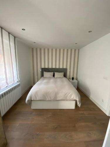 a bedroom with a white bed with striped walls at Alojamiento - Las Murallas de Dulcinea in Avila
