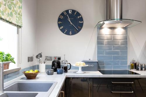 a kitchen with a sink and a clock on the wall at Hen Harrier Lodge in Lancaster