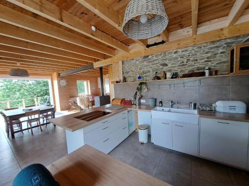 une cuisine avec des armoires blanches et un plafond en bois dans l'établissement Maison Bord de lac de Guerledan, à Guerlédan