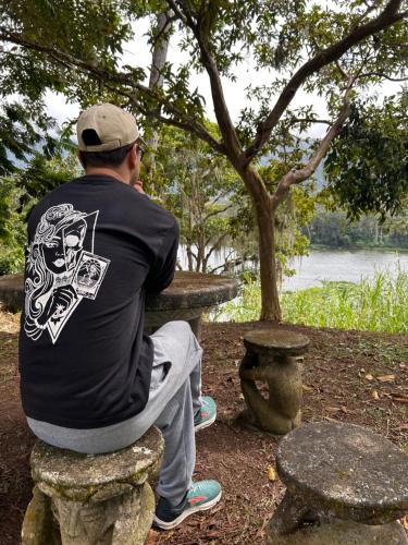 a man sitting on a stone bench looking at the water at Jicote finca de ecoturismo in Cartago