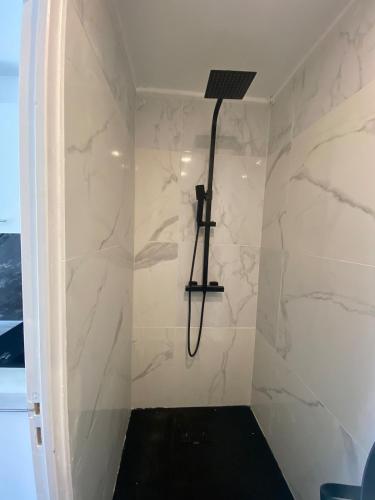La salle de bains est pourvue d'une douche et de murs en marbre blanc. dans l'établissement Chez Nenette & Didi Cozy Independent Duplex, à La Celle-sous-Gouzon