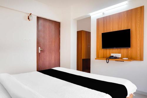 a bedroom with a bed and a flat screen tv at Collection O Lohegaon Pune Airport in Pune