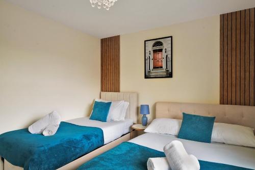 two beds in a room with blue and white at Thames Family Retreat, 2 bed house, Sleeps 6, with Parking and Garden in Thamesmead