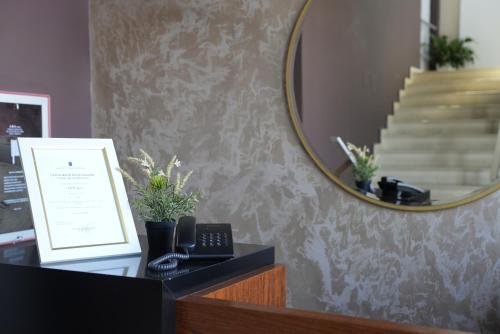 a mirror on a wall next to a desk with a phone at BluePoint Hotel in Tepelenë