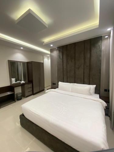 a bedroom with a large white bed with a wooden headboard at سيتي قولد للشقق الفندقيه in Taif