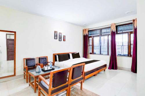 a bedroom with a bed and a desk and windows at Collection O Mall Road Library Chowk in Mussoorie
