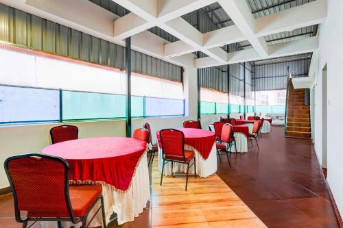 a dining room with red tables and chairs and windows at Collection O Chennai Pallavaram station in Chennai
