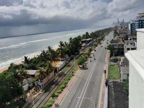 an empty street with palm trees and the ocean at Marine View Apartment - Dehiwala in Dehiwala