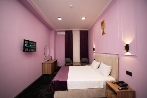 a hotel room with a bed and purple walls at Will Hotel in Baku