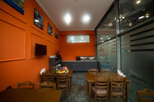 a dining room with orange walls and wooden tables and chairs at Will Hotel in Baku