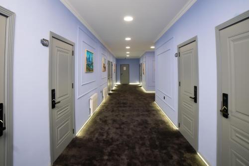 a hallway with white doors and a carpeted floor at Will Hotel in Baku