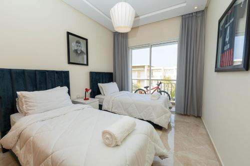 two beds in a bedroom with a large window at Welcome Sidi Rehal Escape 3Beds Sea & Vue Piscine in Sidi Rahal