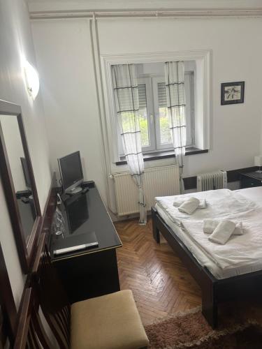 a bedroom with a bed and a desk with a laptop at Prenociste PALIC in Palić