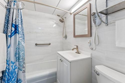 Un baño blanco con lavabo y ducha. en 6201 Ocean Ave, Unit 504 - The Nassau Inn, en Wildwood